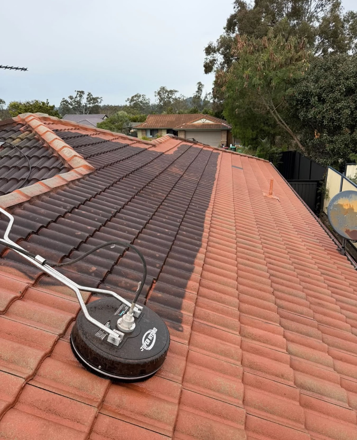 Pressure cleaning half a terracotta tiled roof in Sydney