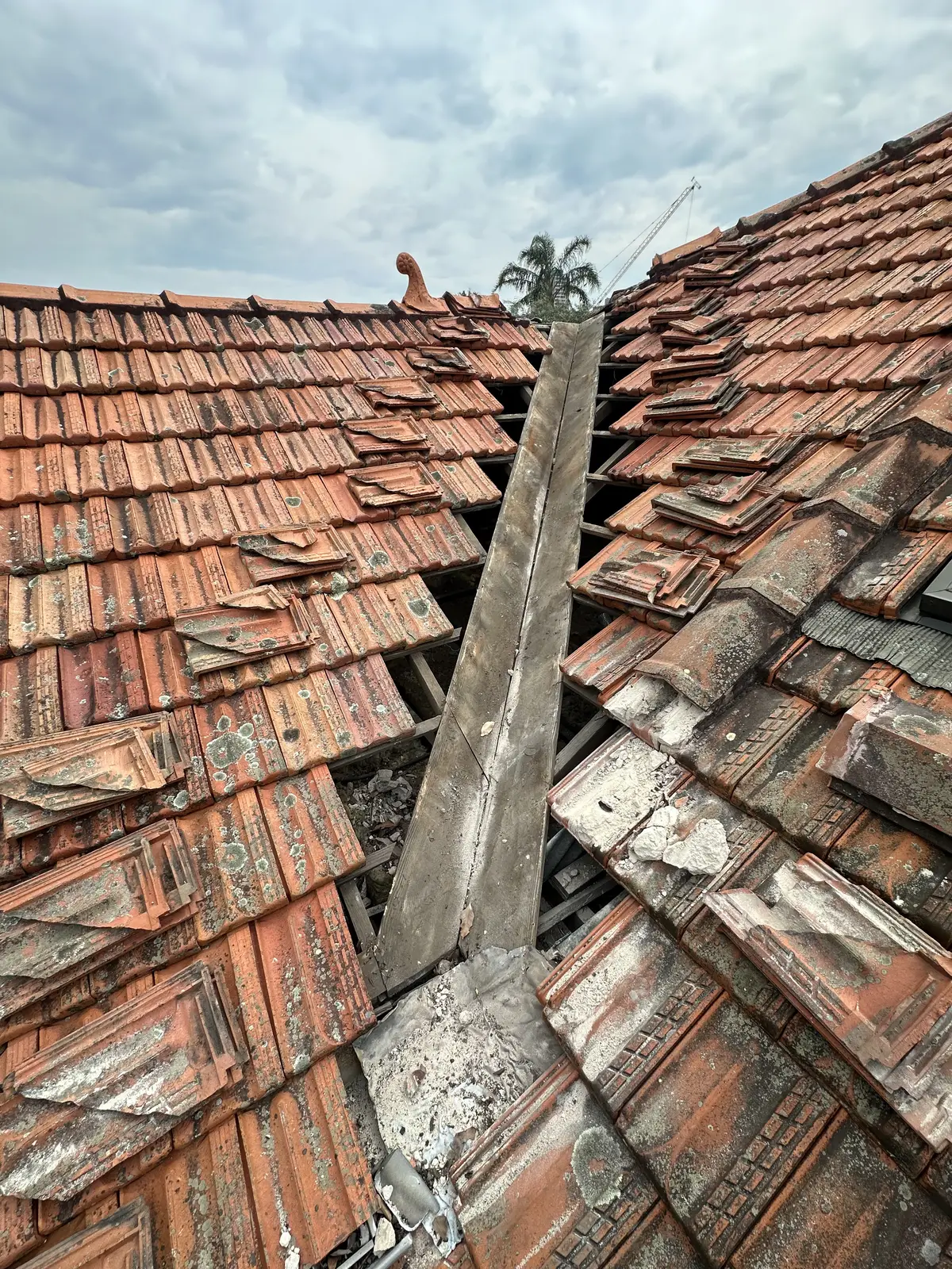 Terracotta tiled roof with storm-damaged tiles torn off around the ridge
